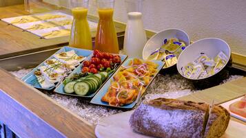 A buffet with various food items, including fruits, vegetables, cheese, and bread.
