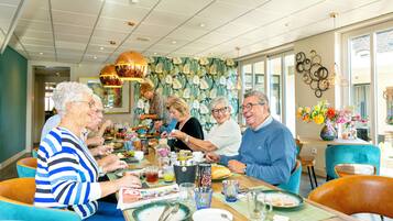 A dining area with a long table, chairs, and various dishes and drinks.