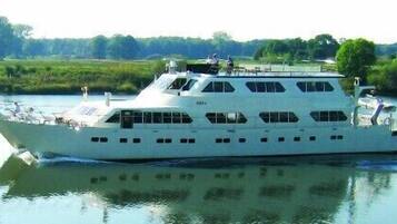 Een grote witte boot met meerdere dekken en ramen, waarschijnlijk gebruikt voor rondvaarten of recreatie.