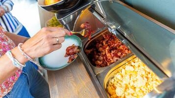 A buffet with various food items including bacon, eggs, and potatoes.