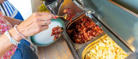 A buffet with various food items including bacon, eggs, and potatoes.