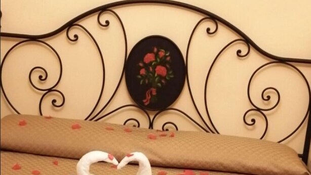 A bed with a swan-shaped towel arrangement and rose petals on the bedspread. - Agostiniana Hotel (Forza d'Agro)