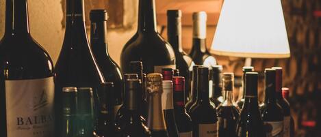 Une collection de bouteilles de vin dans une pièce faiblement éclairée, avec une lampe en arrière-plan.