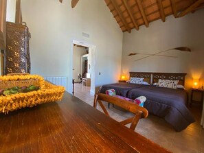 A bedroom with a wooden headboard, a bed with dark bedding, a bedside table with a lamp, and a wicker basket on a wooden table. - Molino la Nava (Montoro)