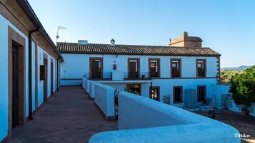 A traditional building with a tiled roof, multiple windows, and a courtyard with a brick floor.