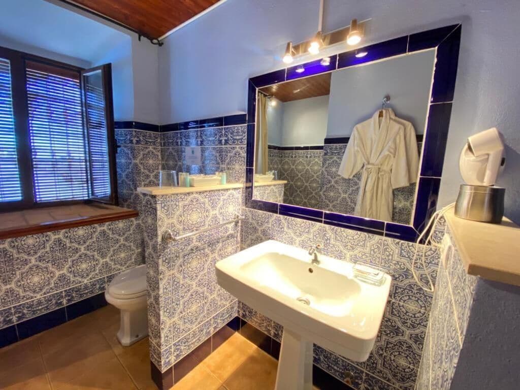 Ein Badezimmer mit einem weißen Waschbecken, einem Spiegel und fliesenbesetztem Boden.