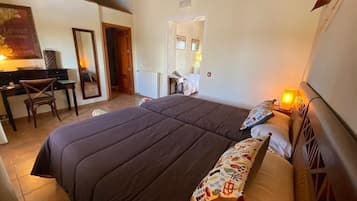 Un dormitorio con una cama grande, un escritorio y una silla. Hay una puerta que da a otra habitación.