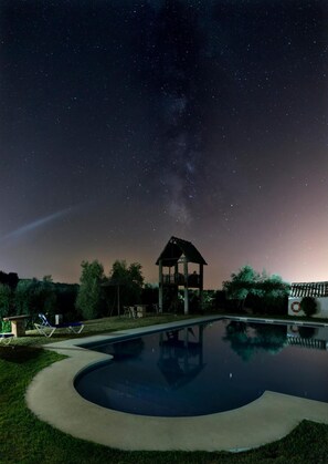 A swimming pool with a wooden gazebo and lounge chairs under a starry night sky. - Molino la Nava (Montoro)