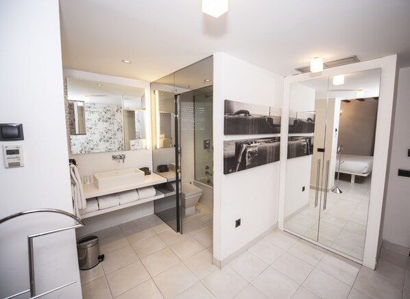 Un baño moderno con cabina de ducha de vidrio, lavamanos blanco y espejo con diseño floral.