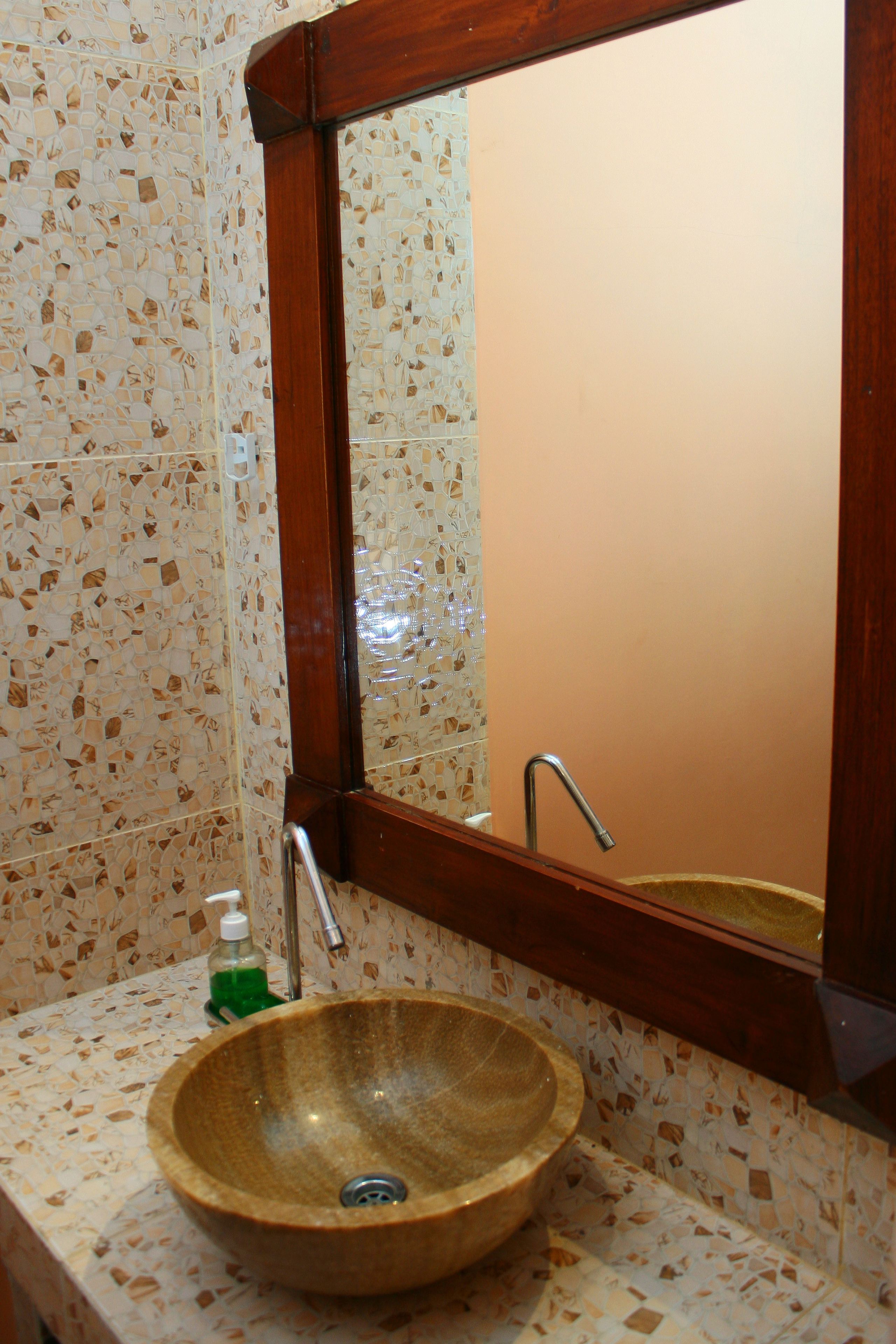 Un baño con salpicadero de mosaicos, un lavamanos de madera, un espejo y un grifo.