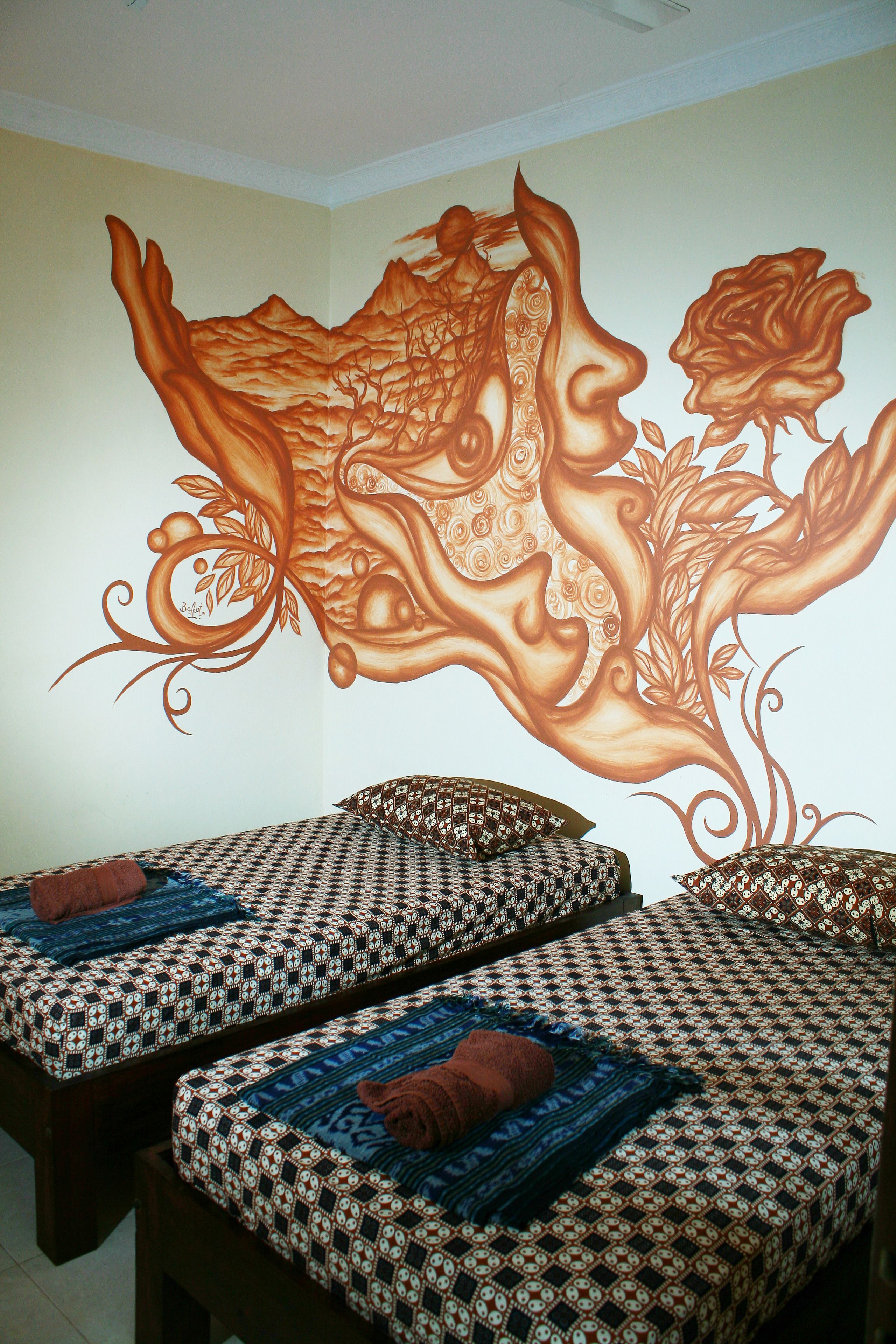 A room with two beds, each with patterned bedding and pillows.