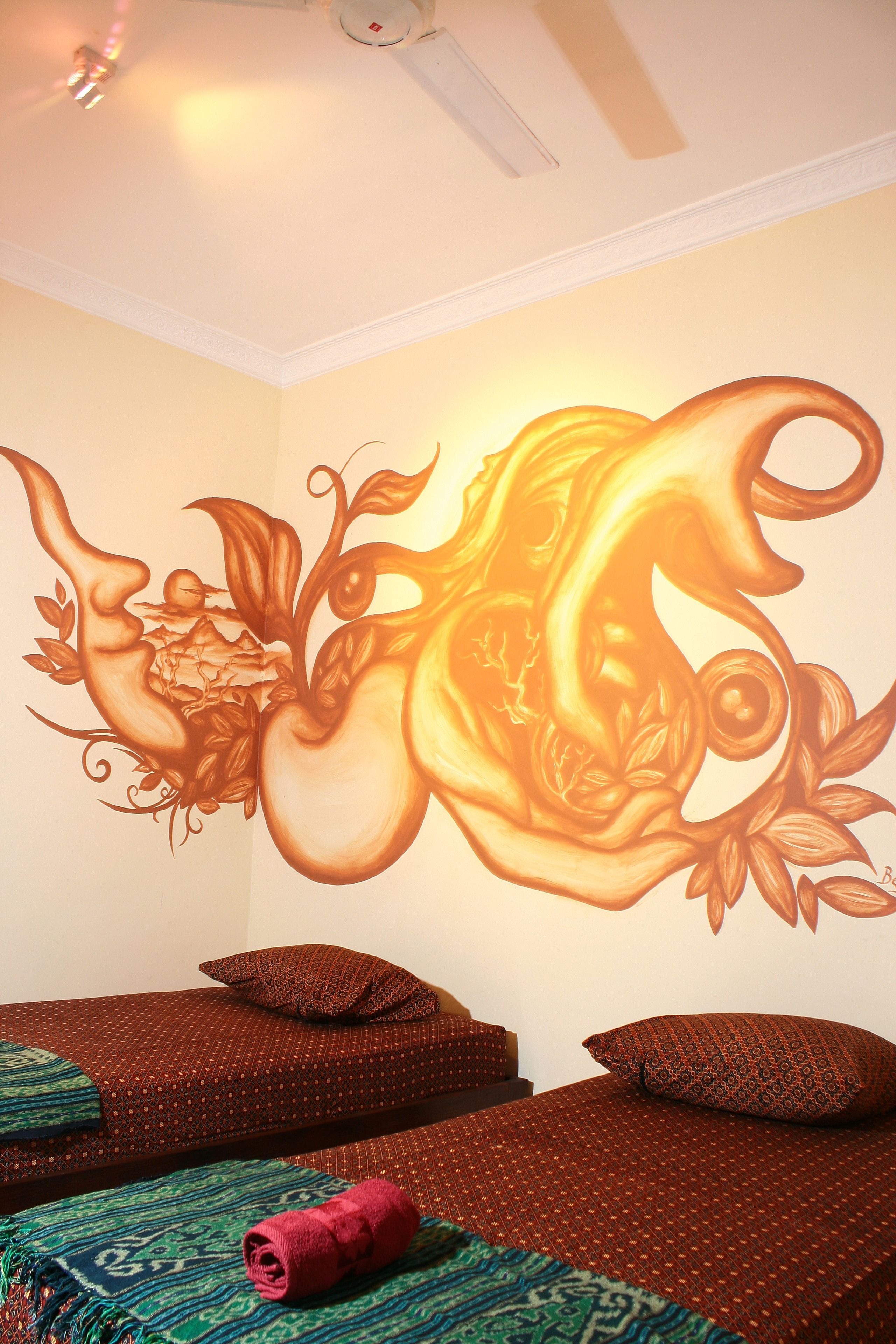 Una habitación con dos camas, ropa de cama estampada y un mural en la pared.
