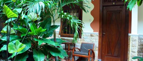 A wooden door with a number plate, a stone wall, and a potted plant in front of a window.