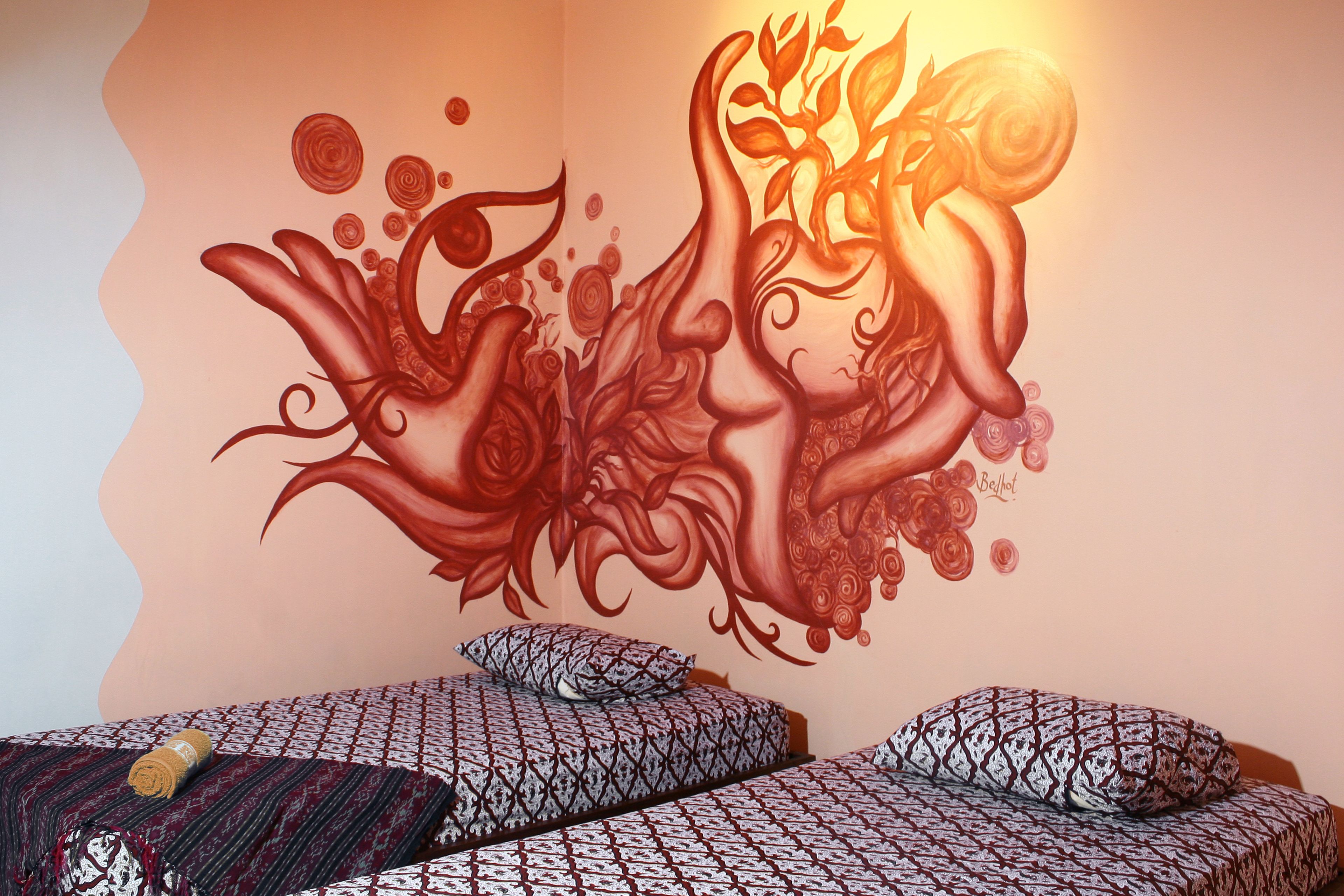 A bedroom with two beds, patterned bedding, and a wall mural.