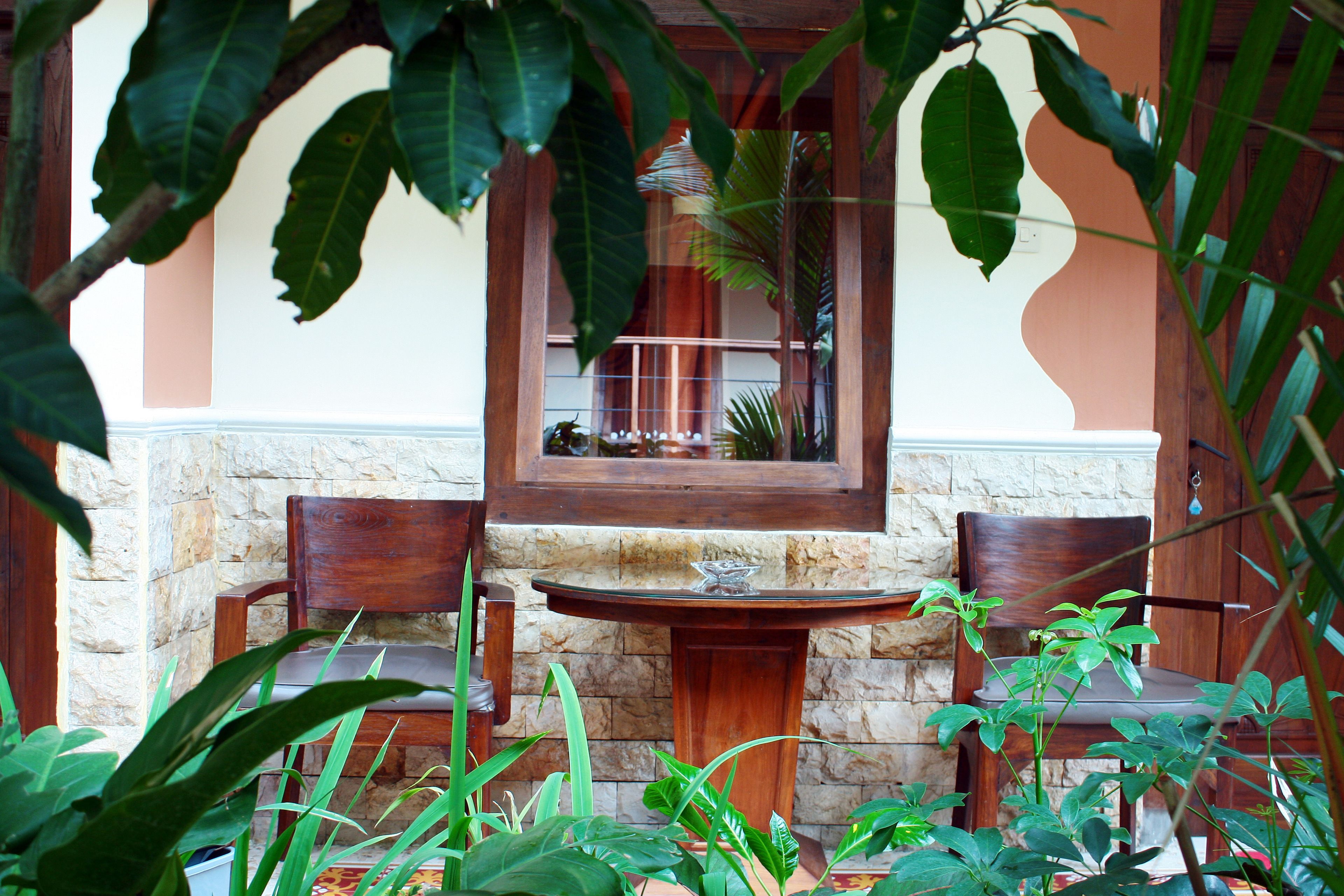 A stone wall with a wooden bench and two chairs.