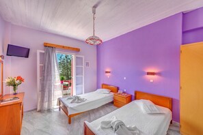 A bedroom with two single beds, a wooden nightstand, a TV, and a window with curtains.