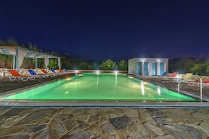 A swimming pool with lounge chairs and a building in the background.