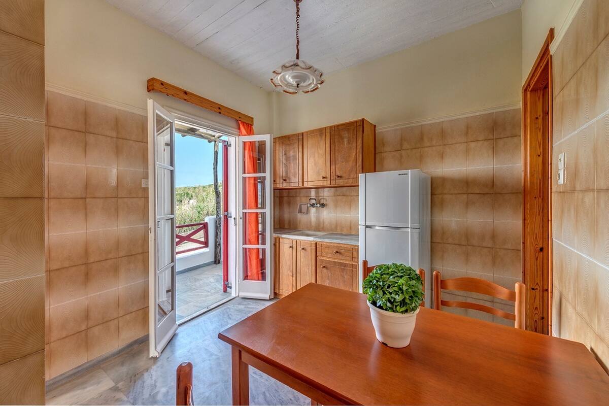 A kitchen with wooden cabinets, a white refrigerator, and a dining table with a potted plant.