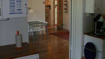 Uma cozinha com piso de madeira, armários brancos e um espaço de refeições com mesa e cadeiras.
