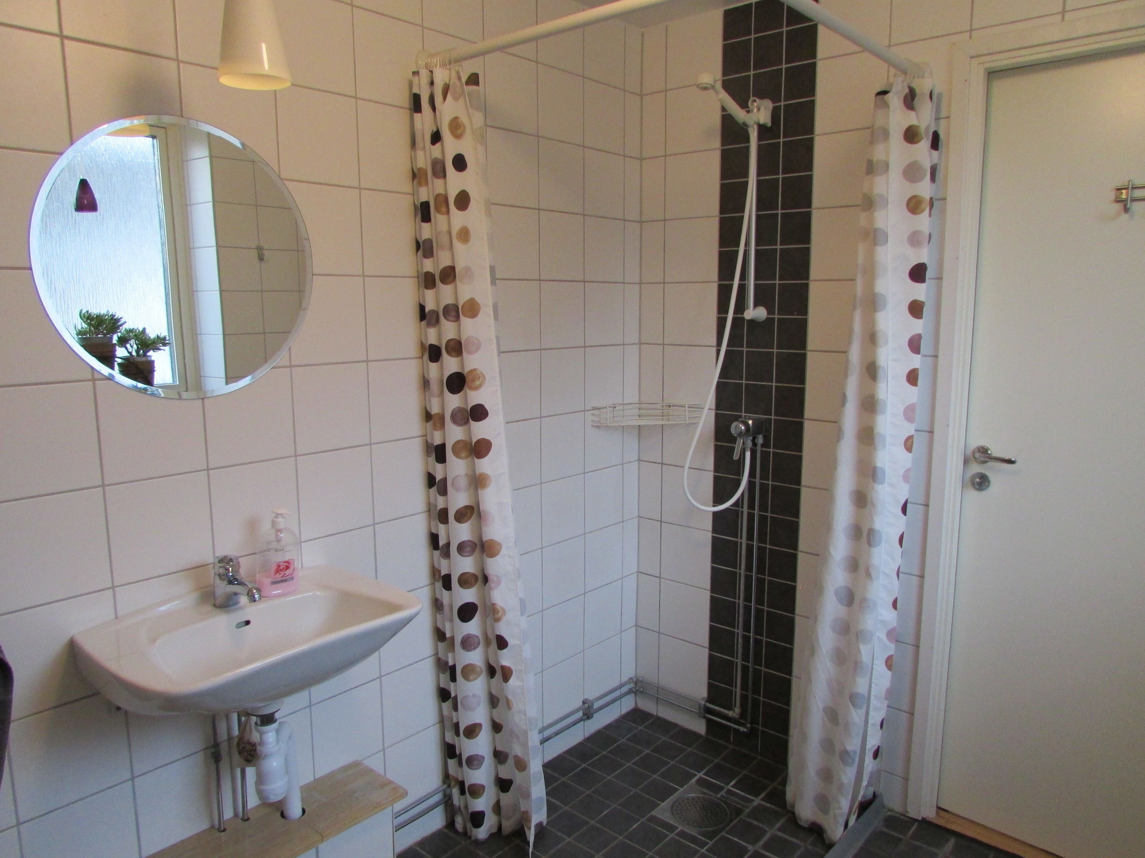 A bathroom with a sink, mirror, shower, and toilet.