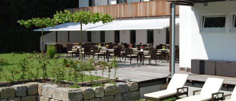 An outdoor patio area with tables and chairs, a wooden deck, and a stone planter.