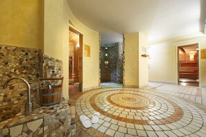 Un baño con piso de mosaicos, un balde de madera y un lavamanos.