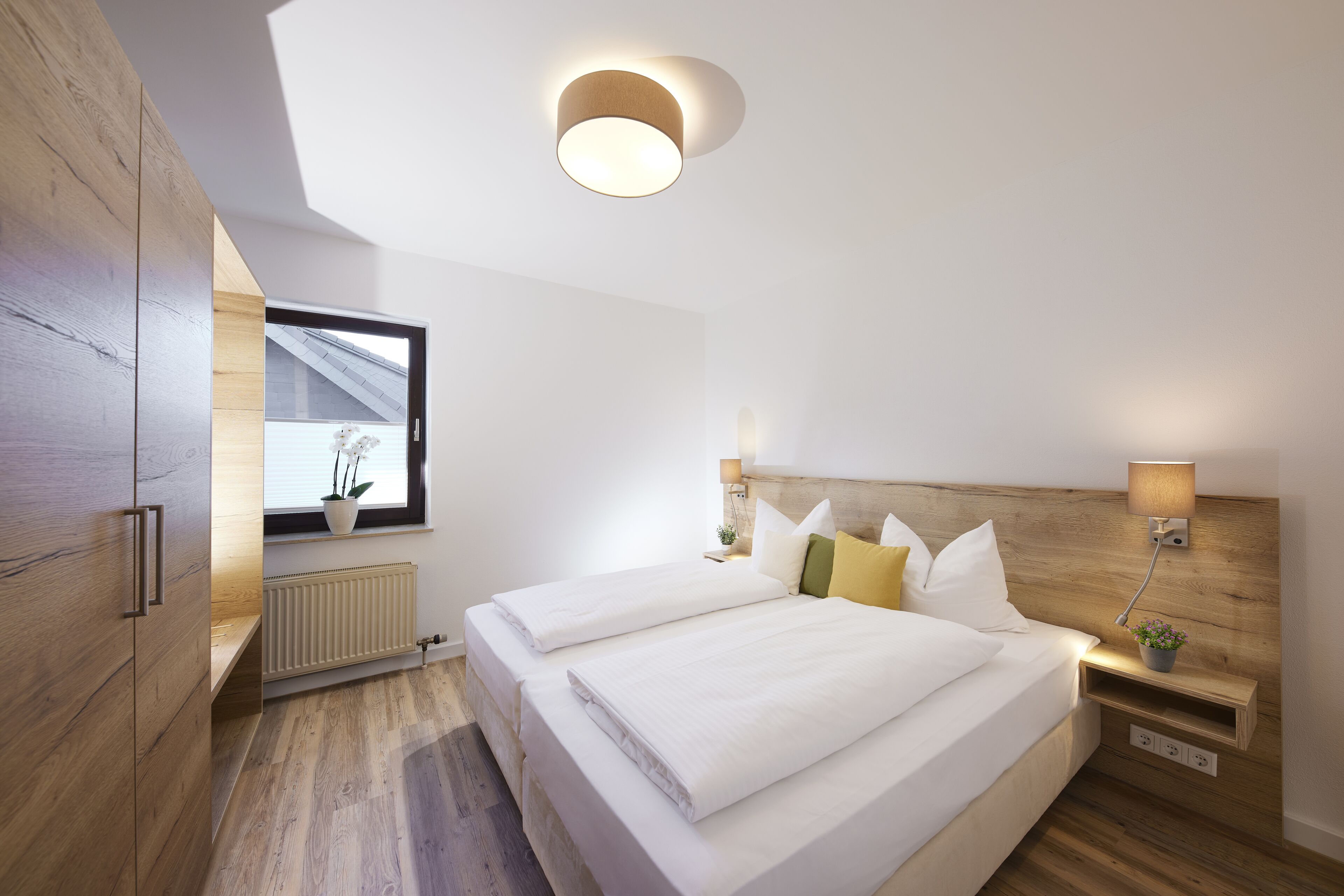 Un dormitorio moderno con una cama grande, cabecera de madera, mesitas de noche y una ventana con vistas.
