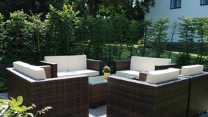 Un patio con mobiliario de mimbre y una mesita con una planta.