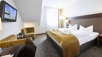 Una camera d'hotel con un letto, una scrivania, una sedia, una televisione e una lampada.