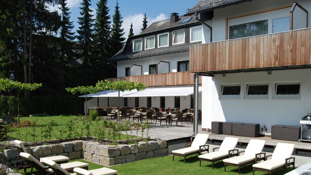 Un patio al aire libre con sillones de descanso, una zona de comedor y una parrilla.
