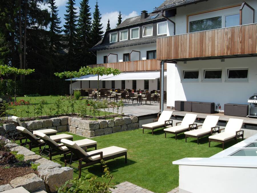 An outdoor patio with lounge chairs, a dining area, and a barbecue grill.