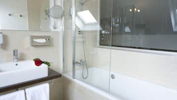 Une salle de bain moderne avec une douche à parois de verre, un lavabo blanc orné d’une rose et un grand miroir.