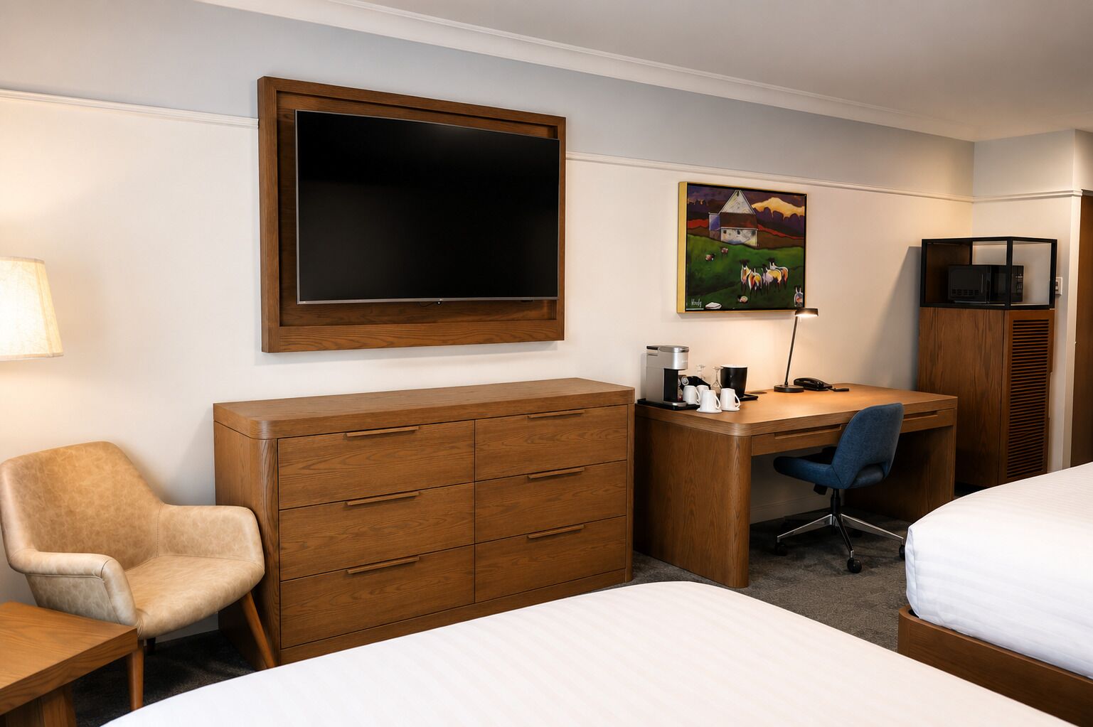 Une chambre d’hôtel avec un lit, un bureau, une chaise, une commode, un téléviseur et un tableau au mur.