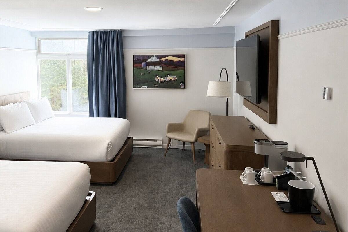 Una habitación de hotel con dos camas, un escritorio con cafetera, televisión y un cuadro en la pared.