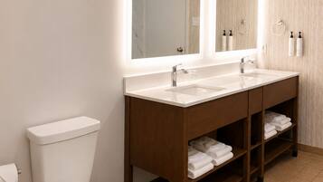 Een moderne badkamer met toilet, een wastafelmeubel met dubbele wastafel en een grote spiegel.