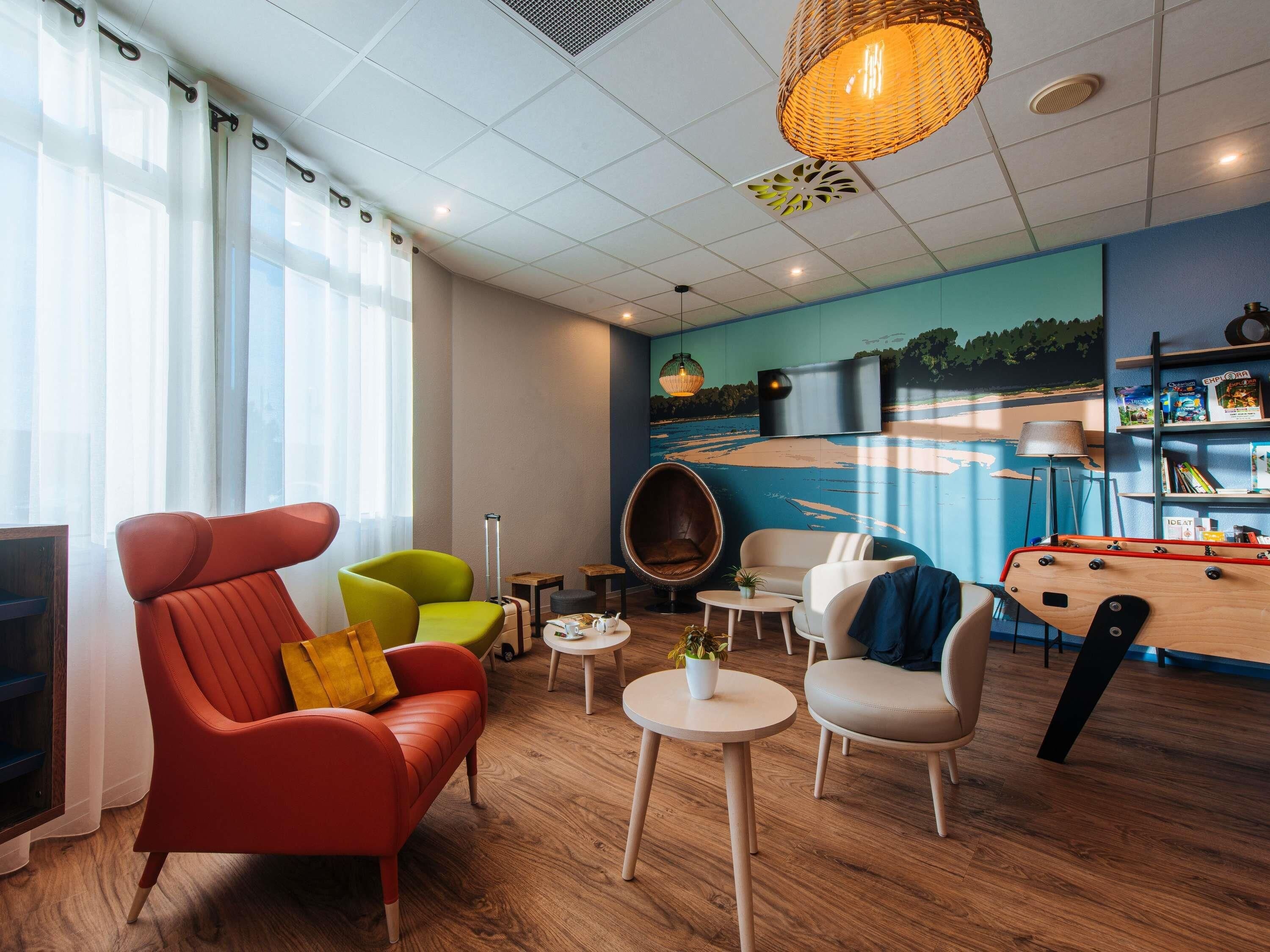 A modern lounge area with a red sofa, green armchair, and a wooden coffee table.
