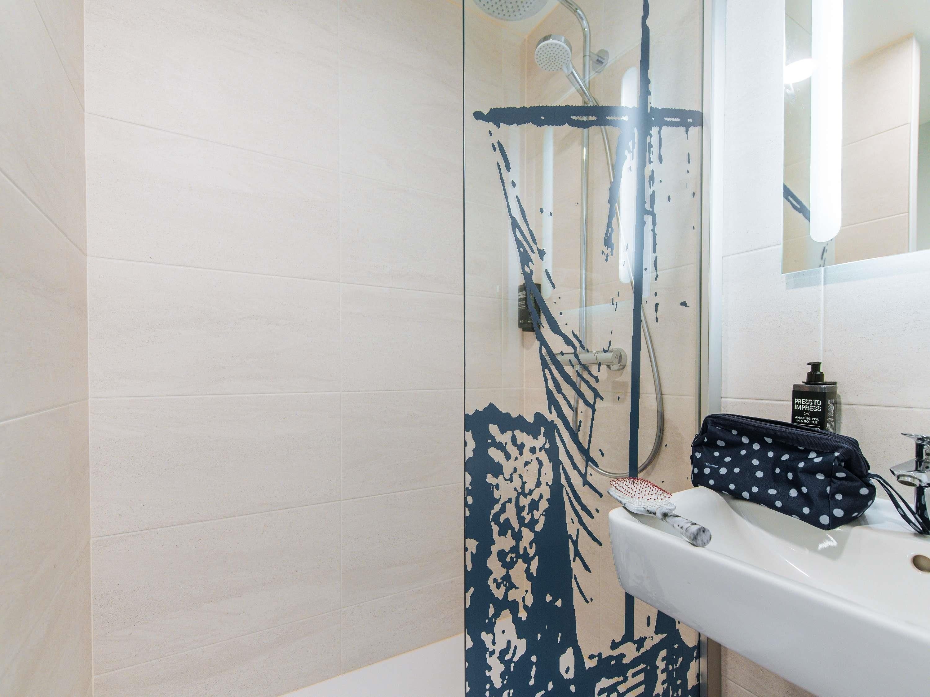 Un baño con ducha, lavamanos y espejo.