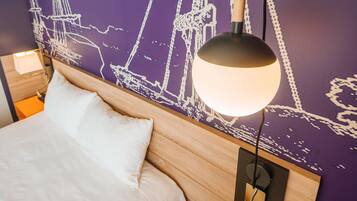 A hotel room with a bed, a nightstand, a lamp, and a wall with a nautical-themed mural.