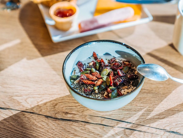 A bowl of granola with seeds and dried fruits on a wooden table.