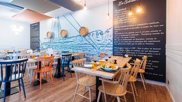 A restaurant interior with wooden tables, chairs, and a wall menu.