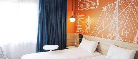 A hotel room with a large bed, a small table, and a wall with a map design.