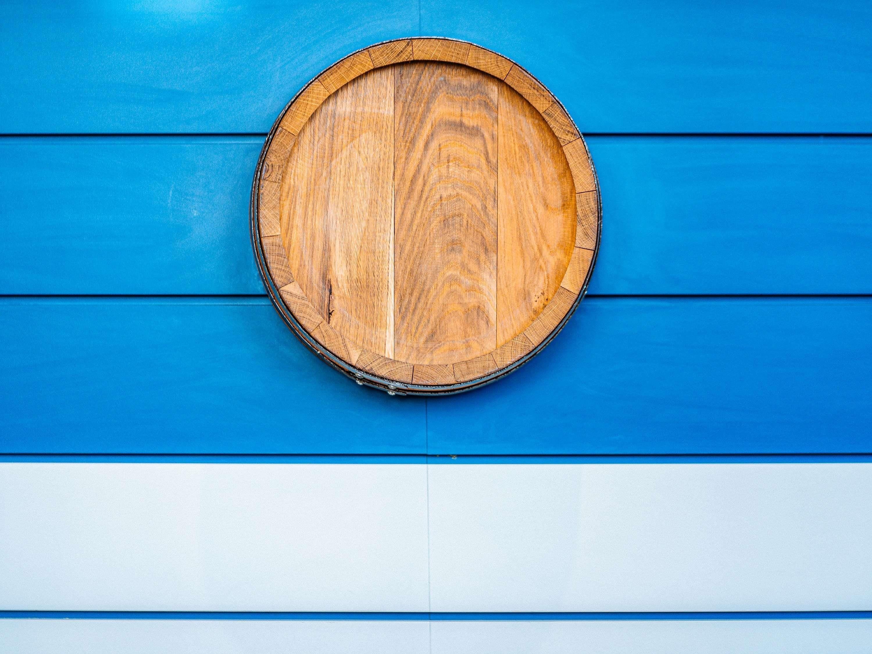 A round wooden object against a blue and white wall.