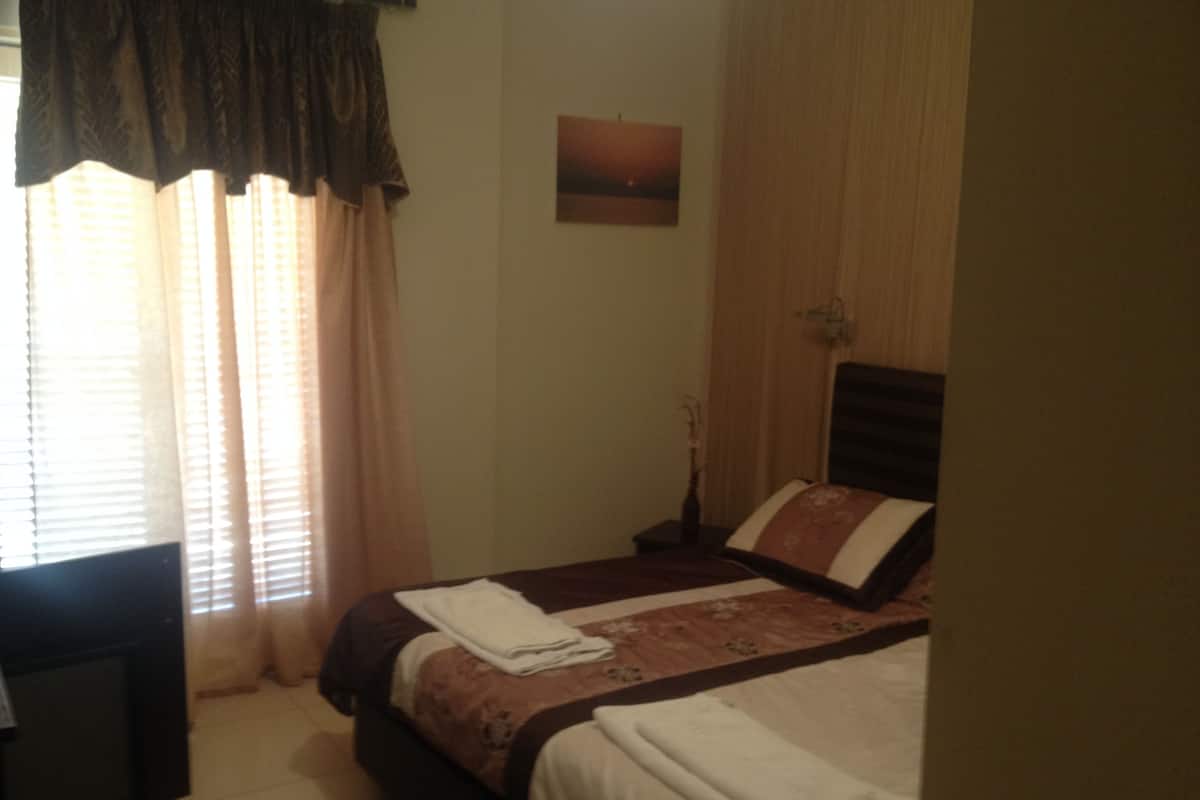 A bedroom with a bed, a nightstand, a lamp, and a painting on the wall.