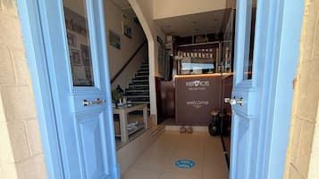 A hotel reception area with a staircase leading to the upper floors.