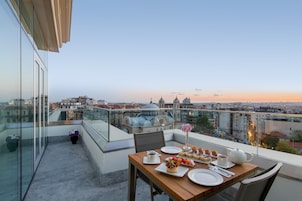 Un tavolo da pranzo su un balcone con vista sulla città, che include una cupola e degli edifici.
