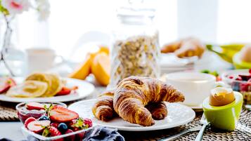 Una colazione con cornetti, frutta e una tazza di caffè.