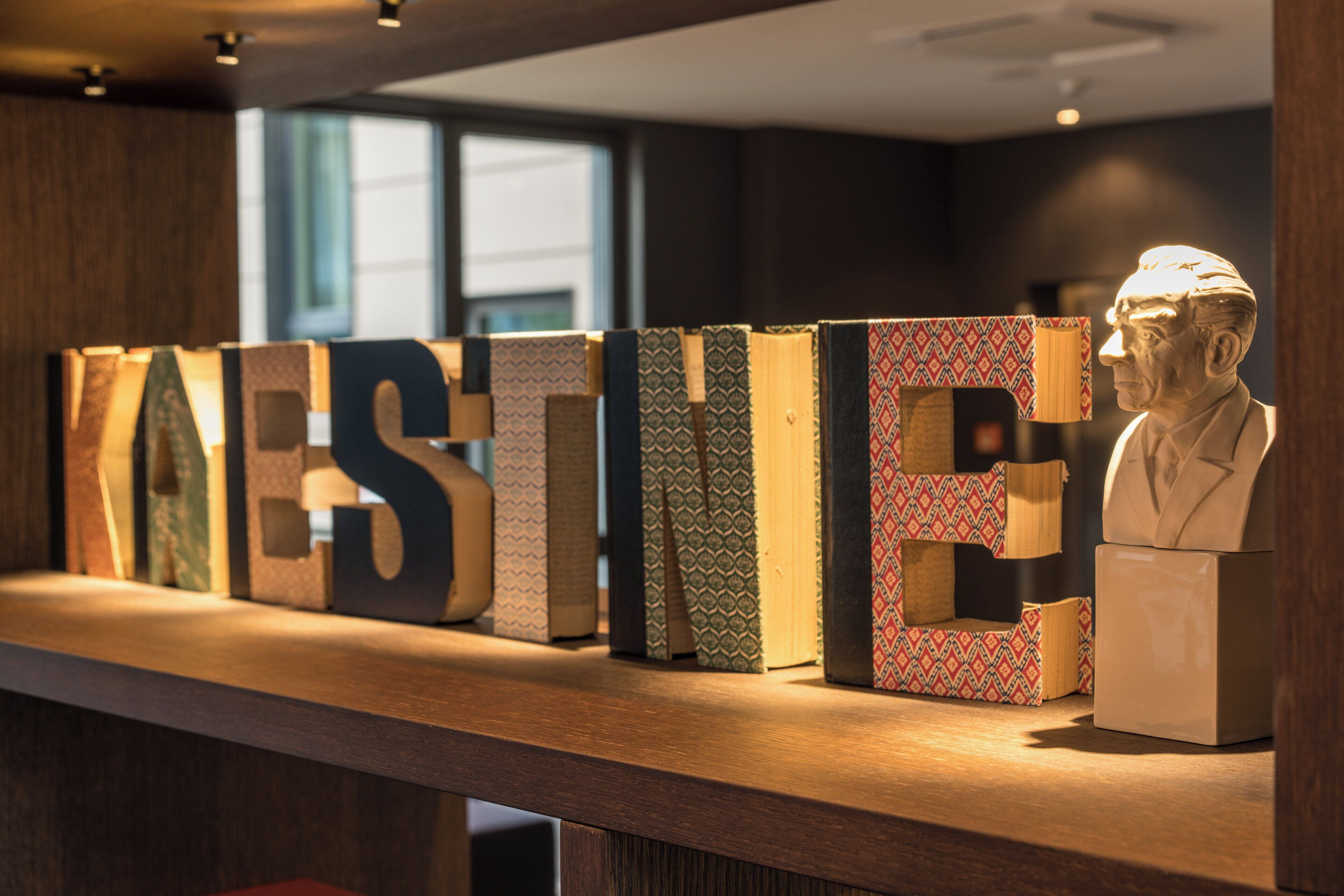 A reception desk with a row of books and a bust sculpture.