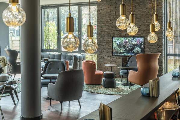 Uma área de estar moderna com parede de pedra, assentos confortáveis e luminárias pendentes.