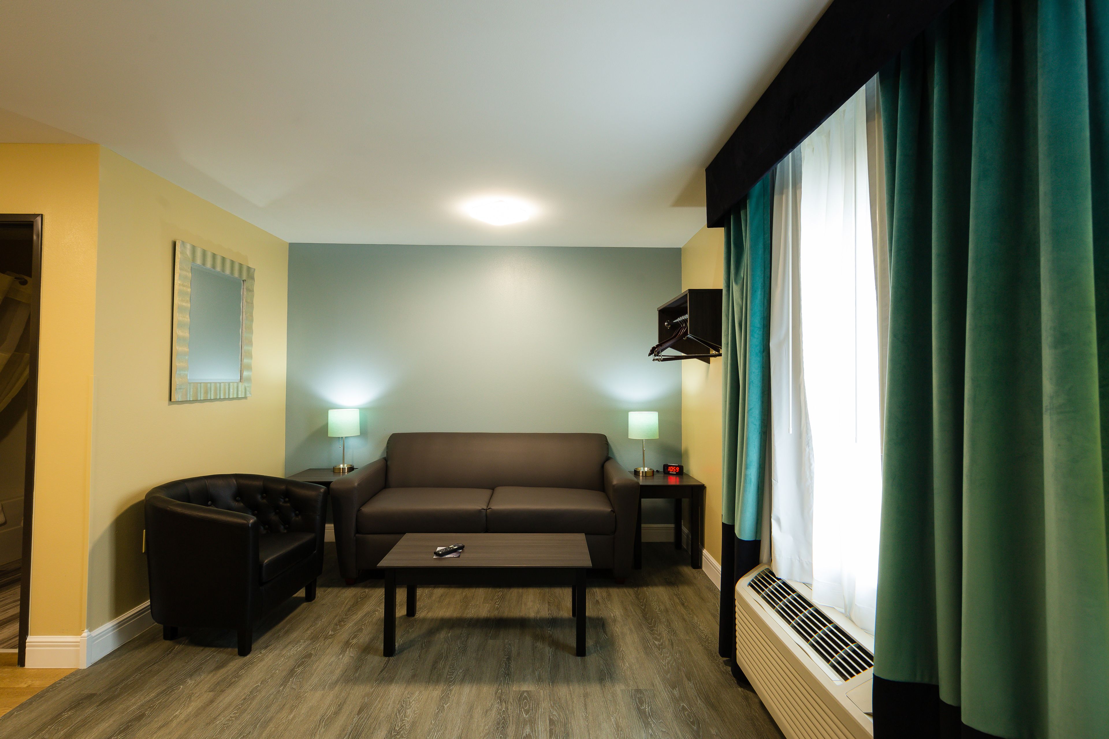 Un salon comprenant un canapé, une table basse, une table d’appoint avec une lampe, et une fenêtre avec des rideaux.