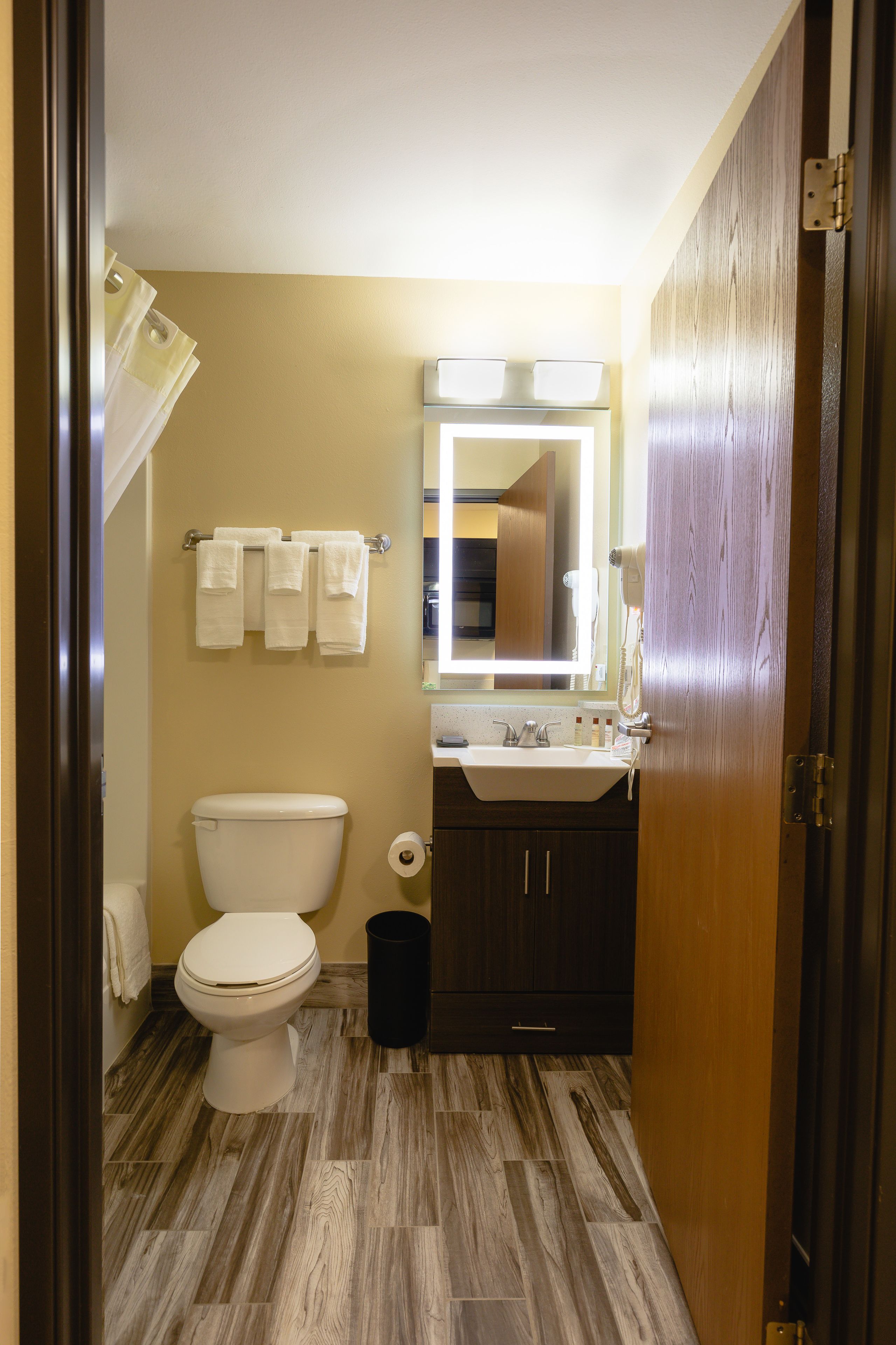 A compact bathroom with a toilet, sink, and mirror.